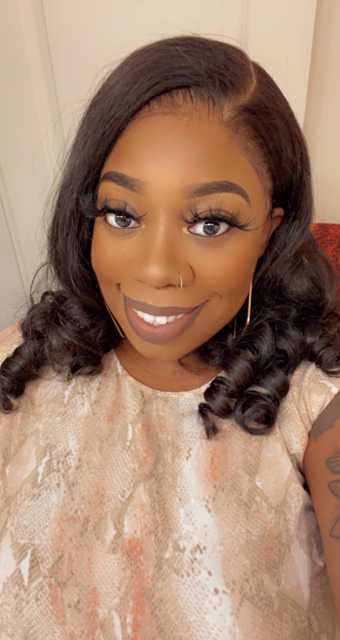 Smiling woman with curled hair and elegant makeup.