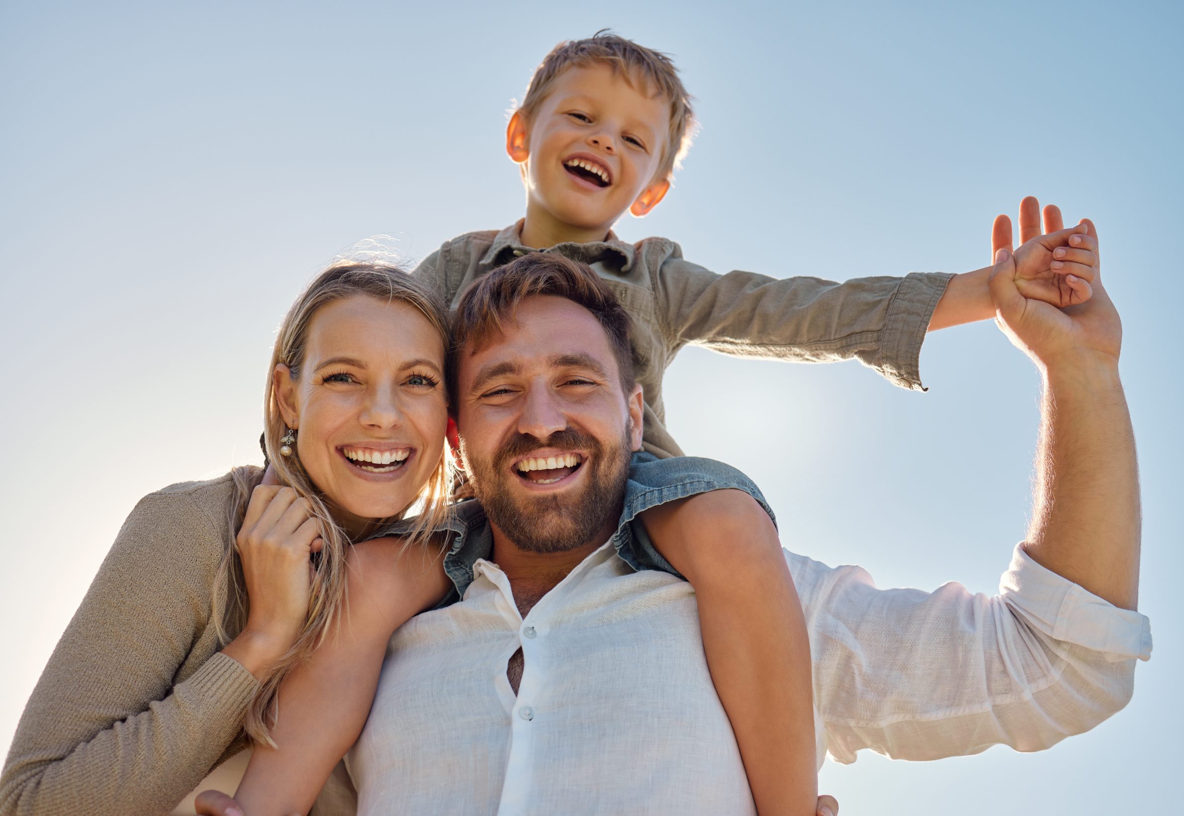 Smiling family with child on shoulders.