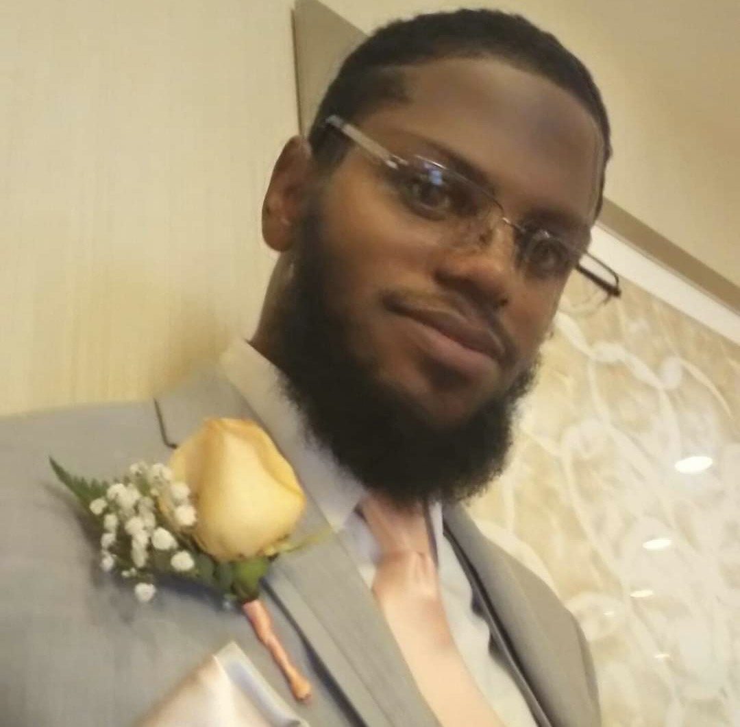 Man in glasses and suit with a boutonniere smiling.